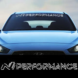 Blue car with 'N Performance' decal on the windshield against a blurred background