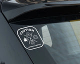 Sticker on a car window with 'Caution Approach Carefully' text and symbols.