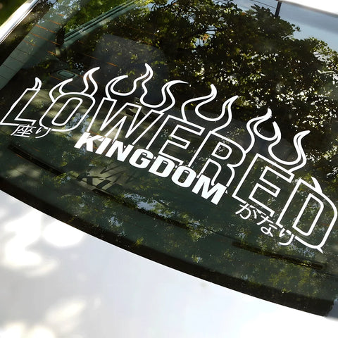 Decal with 'LOWIRED KINGDOM' on a car window with tree reflection