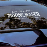 Car window with 'MOONCHASER' decal and reflection of trees.