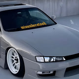 Gray car with a 'misunderstood' sticker on the windshield in an urban setting