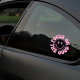 Pink 'Focus on Good' smiley face decal on a car window