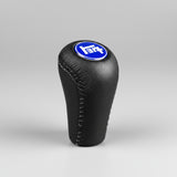Black leather gear shift knob with blue logo on a black background