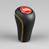 Black leather gear shift knob with colorful stitching and red logo on a black background