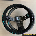 Black steering wheel with decorative elements on a light wooden surface, featuring the TopJDMStore.com logo.