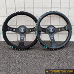 Two black steering wheels with decorative elements on a tiled floor.