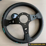 Black steering wheel with a central hub on a light wood surface, featuring the TopJDMStore.com logo.