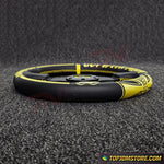 Black and yellow steering wheel cover on a textured black surface with 'TopJDMStore.com' branding.