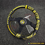 Black and yellow steering wheel with text on a textured gray background