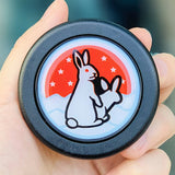 Naughty white rabbit horn button with suggestive bunny illustration on red sun background.